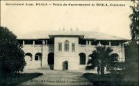 Palais du gouverneur de Duala. – « La ville et le port sont bâtis sur la rive gauche du large Wouri ; il y a des maisons, des bateaux, un hôpital, - naturellement, - tout blanc, un palais du gouvernement pour loger le gouverneur quand il en a assez de son paradoxe de Yaoundé… […] Le palais du gouvernement est une belle construction, - belle, je veux dire grande, et, d’ailleurs, elle n’est pas très laide, - édifiée par les Allemands. Un grand jardin l’entoure, avec des gazons, des arbres, des grandes chauves-souris brunes, qui s’accrochent aux palmiers par grappes, la tête en bas, comme des linges qui sèchent. Il s’avance en terrasse sur le Wouri, qui, ce matin, est couleur de lait, exactement. Il fait beau et bon ». Source : Martet, Jean, Les bâtisseurs de royaumes, Paris, Albin Michel, 1934.