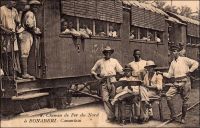Chemin de Fer du Nord à Bonaberi. – La ligne reliant Douala à Nkongsamba est construite entre 1908 et 1911, à l’époque coloniale allemande. On l’appelle alors la « ligne du Nord », bien que ses 172 km de long ne la mènent en réalité pas bien loin dans la partie septentrionale du pays. Le projet initial était, il est vrai, de rallier  N’Gaoundéré et Garoua. De fait, la ligne devint par la suite le « chemin de fer de l’ouest », ce qui est plus conforme à son tracé. Bien plus tard, entre 1964 et 1974, un tronçon joignant Yaoundé à N’Gaoundéré devait effectivement desservir le nord du Cameroun. Equipé d’une voie unique à écartement métrique, le chemin de fer « du nord » devenu « de l’ouest » part, côté capitale économique, depuis le quartier de Bonabéri, sur la rive ouest du Wouri. Pour l’emprunter, les habitants de la ville devaient traverser le fleuve par voie navigable jusqu’à la construction du pont en 1954. – « Je quitte Douala un matin, à l’aube. Michel est venu me chercher au Gouvernement, m’a emmené au port ; nous sommes montés dans une petite vedette à pétrole, nous avons passé le Wouri. Nous sommes arrivés à un endroit qui s’appelle Bonabéri. Là, il y a une gare et un petit train. […] je suis monté dans le train ; le train est parti. On m’a donné un wagon, tout un wagon. Il y a une plateforme à l’arrière du wagon et le wagon est le dernier du train. J’ai pris un fauteuil dans le salon, je me suis assis sur la plateforme et je regarde la petite voie filer dans la forêt des deux côtés. » (1). Sources : (1) Martet, Jean, Les bâtisseurs de royaumes, Paris, Albin Michel, 1934.