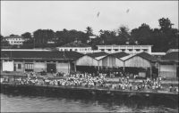 Douala, un coin des quais. - « Le port de Douala, avec balises, chenal et quais. On les a construits sur du poto-poto. Les paquebots y accostent. Seuls ceux qui ont débarqué des passagers ou chargé des marchandises en face des wharfs ou à travers la barre des côtes africaines, savent ce que c’est qu’un quai. » (1). « Des dragages ont été effectués aux postes de mouillage qui peuvent recevoir des navires de 150 mètres de long. Devant la ville il existe 5 postes que peuvent prendre les navires ne désirant pas accoster à quai. On peut aussi mouiller en amont des quais. Les quais ont une longueur de 550 mètres avec des profondeurs au pied de 7 à 10 mètres ; ils bordent a ville et permettent l’accostage de 4 grands bâtiments. En amont le quai dit, du chalandage, où les profondeurs sont de 1 à 3 mètres, prolonge les quais précédents » (2). Sources : (1) J. Wilbois Le Cameroun, éditions Payot, Paris, 1934. (2) Instructions nautiques – Côtes Ouest d’Afrique, Paris, Service Hydrographique de la Marine, 1941.