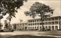 Douala, la place du gouvernement, avec les bâtiments du Crédit Lyonnais et de Printania. -A la recherche d’une formule de type « grands magasins », se démarquant des comptoirs, susceptible de rénover le commerce dans les capitales africaines, la SCOA (Société commerciale de l’Ouest Africain) s’associe à partir de 1952 avec le groupe Printemps pour ouvrir des magasins Printania, et avec Prisunic pour lancer une chaîne de magasins sous l’enseigne Pariscoa. – « La clientèle européenne suffirait à elle seule à faire vivre un certain nombre de commerces (5 à 6000 Européens à Douala, sans compter les « broussards » qui viennent s’y ravitailler) ; la formule ancienne – comptoirs ou boutiques grecques – cherchant à convenir à la fois aux Européens et aux Africains, dont les goûts et les besoins sont souvent différents, semble condamnée à disparaître ». Source : « Douala, porte du Cameroun » (brochure), Douala, Secrétariat social du Cameroun et Chambre de commerce, d’agriculture et d’industrie du Cameroun, 1953.