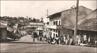 Nkongsamba, route de Bafang, années 1950. - La ville s’est développée avec l’arrivée du chemin de fer, construit entre 1907 et 1912 par les Allemands qui donnèrent alors le nom Nsamba à la localité. La ligne, appelée CFN pour chemin de fer du nord, reliait l’intérieur du pays à la côte, allant de Nkongsamba à Bonabéri, juste à coté de Douala, et passant par Mbanga avec un embranchement sur Kumba. Le chemin de fer, en ouvrant un débouché sur la côte aux productions agricoles de l’Ouest, du Sud-ouest et de la région du Moungo, scelle la prospérité de la ville. De nombreux commerçants européens, allemands, anglais, français et méditerranéens s’y établissent. Les grands comptoirs coloniaux, et tout ce qui compte dans le commerce de l’époque, y installent des succursales ; SCOA, RW King, Tsekenis, CFAO, SHO, Compagnie soudanaise, Olympius, Panafric, les établissements Mercier, John Holt, Paterson Zochonis… La ville est dotée de services officiels, et devient un centre administratif en 1923, succédant dans ce rôle à la localité de Baré. - Le tronçon de chemin de fer reliant Douala à Yaoundé, long de 262 km, fut construit entre 1908 et 1927. Il fut ensuite enrichi d’une bretelle de 30 km reliant Ngoumou à Mbalmayo, construite entre 1927 et 1933. Le tronçon allant vers le nord du pays, entre Yaoundé et Ngaoundéré, (long de 622 km) fut construit bien plus tardivement, entre 1964 et 1974.