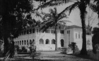 Douala, palais du gouverneur. – « La ville et le port sont bâtis sur la rive gauche du large Wouri ; il y a des maisons, des bateaux, un hôpital, - naturellement, - tout blanc, un palais du gouvernement pour loger le gouverneur quand il en a assez de son paradoxe de Yaoundé… […] Le palais du gouvernement est une belle construction, - belle, je veux dire grande, et, d’ailleurs, elle n’est pas très laide, - édifiée par les Allemands. Un grand jardin l’entoure, avec des gazons, des arbres, des grandes chauves-souris brunes, qui s’accrochent aux palmiers par grappes, la tête en bas, comme des linges qui sèchent. Il s’avance en terrasse sur le Wouri, qui, ce matin, est couleur de lait, exactement. Il fait beau et bon ». Source : Martet, Jean, Les bâtisseurs de royaumes, Paris, Albin Michel, 1934.