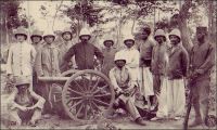 Section d’artillerie de la colonne de répression des N’gbans. - Le groupe des N’gbans, un des plus importants de la grande famille des Baoulés, ne se montre pas très accueillant face à l’entreprise coloniale. « Indépendants, braves, tenaces, chasseurs adroits et infatigables, confiants dans leurs forêts et fourrés impénétrables,[…]ils se sont toujours montrés adversaires redoutables et n'ont jamais voulu s'avouer complètement vaincus. Dès nos premières tentatives de pénétration en Côte d'Ivoire, ils opposent, à Singrobo, une résistance opiniâtre à la colonne Monteil; en 1902 et 1903, ils font subir des pertes nombreuses aux petites colonnes chargées de les punir des attaques qu'ils ont dirigées contre les convois de la ligne d'étapes ; ces colonnes terminées, mais non suivies du désarmement, ils ne payent pas l'amende de guerre qui leur a été infligée », explique Gabriel Angoulvant (1872-1932), le gouverneur général de Côte d’Ivoire de 1908 à 1916, à propos des actions de pacification menées à son initiative. Saisissant le prétexte de les désarmer –ils possèdent 2100 fusils, selon lui-, il envoie une colonne de tirailleurs solidement équipée, appuyée d’une artillerie légère, et parvient à soumettre la soixantaine de villages n’gbans entre avril et septembre 1910. Sources : Angoulvant, G., La pacification de la Côte d’Ivoire, Paris, éd. Emile Larose, 1916.