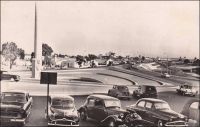 Abidjan, vue du pont de la poste. – Il s’agit en fait d’une vue de la place Lapalud, aux extrémités opposées de laquelle se trouvent effectivement la Poste et  le pont Houphouët-Boigny. Construite en 1957, cette place est inaugurée le 15 mars 1958 en même temps que le pont qu’elle prolonge. En forme d’hémicycle, elle constitue la pointe sud de la presqu’île lagunaire du Plateau. Elle porte en son centre un monument emblématique, constitué d'une colonne verticale en dessous de laquelle se trouve la statue d'une femme portant sur sa tête un panier rempli de feuilles. La légende veut qu’une femme rencontrée un jour en ce lieu soit à l’origine du nom de l’actuelle capitale économique de la Côte d’Ivoire. Ainsi, au XVIIIème siècle, des français, venus reconnaître l’endroit, croisèrent là une femme rentrant de la cueillette. Tandis qu’ils lui demandaient d’où elle venait, elle répondit « t'chan m'bi djan », ce qui signifie « j'étais allé couper des feuilles » en Ebrié. Transcrit phonétiquement, ce que les explorateurs avaient pris pour le nom du lieu, devait rester. La place, qui portait le nom de Maurice-Pierre Lapalud, gouverneur de la Côte d’Ivoire entre 1925 et 1930, fut rebaptisée en 1961 place de la République.