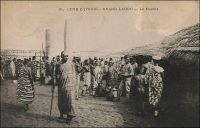 Grand Lahou, le marché. – « On est surpris en mettant le pied en Côte d’Ivoire de croiser des indigènes drapés avec dignité dans de véritables toges à la mode romaine, un bras et une épaule laissés libres. Ici, même le coloris du tissu offre de plus grandes variétés [que chez les Ouolofs, les Mandingues, les Mossis et les Foulahs qui affectionnent les boubous blancs] ; teinte unie ou larges rayures, dessins d’animaux et de fleurs, mais jamais de damiers. » Source : Bozon, L., Despoins, J., Lacharrière de, L., Leyritz, A., Marquis-Sébie, D., Cécile de Multhedo, Mme, Rectenwald, G., Reste, J-F., Le domaine colonial français, Paris, Editions du Cygne, 1929.