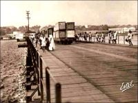 Abidjan, le pont de Treichville. – Cet ouvrage un peu primitif, un pont flottant, avait été édifié en 1931, approximativement à l’emplacement de l’actuel pont Houphouët Boigny, lequel a été construit en 1957. Franchissant la lagune Ebrié, il reliait les quartiers du Plateau et de Treichville. Ces quartiers sont issus du déguerpissement de villages Tchaman (le nom original des occupants des lieux, rebaptisés Ebrié par le colonisateur, en empruntant un terme péjoratif employé par la communauté abouré de Grand Bassam). Ainsi, le village de Dugbeyo, situé au sud du Plateau, est déplacé de l’autre côté de la lagune à Anoumabo, 