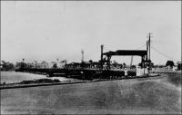 Abidjan, le pont de Treichville. – Cet ouvrage un peu primitif, un pont flottant, avait été édifié en 1931, approximativement à l’emplacement de l’actuel pont Houphouët Boigny, lequel a été construit en 1957. Franchissant la lagune Ebrié, il reliait les quartiers du Plateau et de Treichville. Ces quartiers sont issus du déguerpissement de villages Tchaman (le nom original des occupants des lieux, rebaptisés Ebrié par le colonisateur, en empruntant un terme péjoratif employé par la communauté abouré de Grand Bassam). Ainsi, le village de Dugbeyo, situé au sud du Plateau, est déplacé de l’autre côté de la lagune à Anoumabo, 