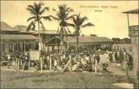 Seccondee, market. - La ville côtière de Seccondee (aussi orthographié Sekondi), dans l’Ouest de la Gold Coast, connait un important essor au tout début du XXème siècle. Elle bénéficie, après la guerre de 1900-1901 qui a permis de soumettre le pays ashanti, de gros investissements en infrastructures destinés à évacuer les richesses provenant des nouveaux territoires septentrionaux. Ainsi, une ligne de chemin de fer reliant Kumasi est déployée à partir de 1903 et un nouveau port est ouvert au trafic durant la décennie suivante. Ce dispositif permet d’acheminer le cacao, dont l’agriculture se développe, les bois tropicaux et les produits miniers et en particulier l’or dont l’extraction a bondit grâce aux investissements européens. La ville s’est développée autour du site d’un ancien fort hollandais du XVIIème siècle (une soixantaine de forts sont bâtis le long des 500 km de côtes de l’actuel Ghana à partir du XVème siècle par plusieurs puissances européennes). La ville voisine de Takoradi, sur le site d’un ancien fort anglais à quelques kilomètres à l’ouest de Sekondi, se développe à son tour dans les années suivant la première guerre mondiale. Elle est en effet choisie, par le gouverneur Gordon Guggisberg, pour recevoir le port en eau profonde qui portera le développement économique de la colonie. Les deux villes sont officiellement réunies en 1946, sous le nom de Sekondi-Takoradi.