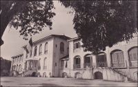 Conakry, le palais du gouverneur. – Bâti entre fin 1889 et mi 1890, cet hôtel cossu devait en imposer : « Les indigènes sentiront l’autorité et la respecteront davantage en voyant une construction plus grandiose et plus en harmonie avec le grade du haut-fonctionnaire qui l’habitera », écrivait le conducteur des travaux dans un rapport, juste avant le début du chantier (1). Il est vrai que le premier résident à avoir représenté la France sur place, le Dr Péreton, arrivé en 1885, avait été bien mal loti. Faute de résidence, il était resté longtemps l’hôte de la maison de commerce SCOA, dans des conditions très précaires. De fait, le palais fut construit massif : 21 X 17 m. pour une hauteur de plus de 15 m., avant même l’ajout dès 1892 de deux ailes.  De plus, il bénéficiait d’un confort sophistiqué, notamment grâce à des circulations d’air, ménagées dans le soubassement, protégées par des grilles en fontes, et dans les combles. Premier grand édifice érigé à Conakry, il devait rester le siège du gouverneur de la colonie, jusqu’à l’indépendance, le 2 octobre 1958. Et il n’échappa pas aux conditions tendues du divorce entre Paris et la Guinée : « Les Français en partant ont détruit les archives, ils ont tout emporté. Le palais du gouverneur, qui sera plus tard la résidence du chef de l’Etat, a été vidé de tout son contenu. La vaisselle qu’ils n’ont pas pu emporter, ils l’ont brisée [...] et nous avons débuté avec nos affaires personnelles » expliquait récemment Andrée Sékou Touré, la femme du premier président de la Guinée indépendante (2). Le palais, que l’on assimilait désormais à la funeste mémoire de ce dernier occupant, fut rasé l’année même de sa disparition en 1984. Le nouveau palais présidentiel, construit pour son successeur, devait à son tour être détruit par des tirs d’artillerie lors d’une mutinerie de l’armée, en 2005. Sources : (1) cité par Odile Goerg, dans Soulilou, J. (éditeur scientifique), Rives coloniale, Paris, éditions Parenthèses et éditions de l’Orstom, 1993. (2) interrogée en 2009  pour l’émission La Nouvelle fabrique de l’Histoire, série Boulevards des indépendances, sur France Culture.
