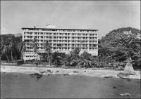 Conakry, l’Hôtel de France. – « Pour atteindre le port, les navires doivent contourner les îles Los et défiler venant du sud entre la cité rouge et verte des « Bauxites du Midi » fixée dans les îles, et le quartier résidentiel de Conakry, bouquet vert d’où jaillissent de puissants buildings de dix à quinze étages, l’hôtel de France et aussi la coupole de la cathédrale avec ses deux tours. […] on y goutte, aussi un peu, le confort de l’hôtel de France, achevé en 1954 et qui  représente au bord de la mer, face aux îles, avec l’immense rotonde ventilée de sa salle à manger, un de ces haut lieux de rencontre où la camaraderie facile des Blancs d’Afrique s’exprime avec aisance et légèreté. » Source : La Guinée Française, Cahiers Charles de Foucauld, Paris, 1957.