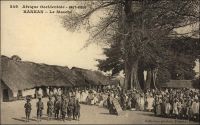 Kankan, le marché. (en 1905). – « Arrivée à la gare de Kankan peu avant midi. Les chefs indigènes, dont un descendant de Samory, viennent nous voir à la gare, drapés, la tête enveloppée de linges blancs, assez semblables à des Flamands du XVème  siècle. Dehors, la milice composée d’anciens tirailleurs, khaki et rouge, porte les armes. Alors éclate, comme une bombe sous le soleil, dans la poussière, avec une brusquerie extraordinaire, mon premier tam-tam d’Afrique »(1). « Jusqu’en 1911 l’orientation soudanienne demeura  prépondérante : les marchandises d’importation arrivaient de Bamako à Kouroussa (terminus des 400 km du bief navigable supérieur du Niger) et à Kankan (par le Milo). La construction du chemin de fer et celle du réseau routier ont renversé l’orientation traditionnelles des courants d’échange au bénéfice de Conakry et donné à Kankan un nouvel essor » (2). Sources : (1) Morand, Paul, A.O.F. de Paris à Tombouctou, Paris, Flammarion, 1928 ; (2) Suret-Canale, Jean, La République de Guinée, Paris, Editions Sociales, 1970. - Cette carte fait partie du travail du célèbre photographe et éditeur dakarois Edmond Fortier (1862-1928) à qui l’on doit une somme importante de clichés sur toute l’Afrique de l’Ouest. M. Fortier tenait boutique non loin du marché Kermel, à l’angle de la rue Dagorne et du boulevard Pinet-Laprade. Cette photo doit dater de 1905. Edmond Fortier avait effectué un voyage en Guinée en 1902 ou 1903, mais il semble qu’il soit allé à Kankan par le fleuve, comme cela se faisait avant l’arrivée du chemin de fer, depuis Bamako, à l’occasion d’un périple au Soudan français en 1905.