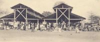 Kindia, le marché vers 1900. – Chef-lieu du cercle du même nom, la ville de Kindia est caractérisée par « une grande rue principale allant de la Résidence [du commandant de cercle] à la gare [ligne Conakry-Kankan], en passant par la place du marché… […] La population, en dehors de l’élément fonctionnaire et militaire, comprend essentiellement les planteurs et les commerçants. » source Guid’AOF, Dakar, 1948.