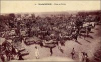 Ouagadougou.  Foire au coton. – Le coton joue un rôle fondamental dans l’histoire et l’économie de la Haute-Volta d’hier et du Burkina Faso d’aujourd’hui. Traditionnellement, il est cultivé en marge des activités vivrières, pour répondre aux seuls besoins locaux (habillement, linges rituels et production de bandes tissées utilisées comme monnaie d’échange dans les transactions commerciales). La matière première est égrainée, filée et tissée au village. Les souches utilisées proviennent d’Afrique de l’est, du continent indien et, à partir du XVIIème siècle, d’Amérique à la faveur de la traite transatlantique. Les rendements et le travail consacré à cette culture sont faibles. Mais l’ère coloniale change la donne. D’abord le coton devient une culture de rente, susceptible de procurer des revenus monétaires aux paysans, et sa commercialisation se développe, comme ici au marché d’Ouagadougou. Puis les nouvelles autorités s’en saisissent, l’enjeu étant pour la métropole de s’affranchir de la dépendance au coton américain, en assurant un approvisionnement régulier pour l’industrie textile nationale avec la production voltaïque, comme les Anglais avec leur colonie indienne. Le premier gouverneur de Haute-Volta, Edouard Hesling, entend en faire le moteur de la mise en valeur du territoire. Il rend donc sa culture obligatoire, organisée autour de champs de coton collectifs villageois, à raison de 4 hectares pour 100 habitants ! Cette intense pression porte un temps ses fruits, et la production décolle avant de retomber tandis que la main d’œuvre déserte le territoire pour aller chercher l’embauche sous des cieux plus cléments, et notamment en Gold Coast britannique voisine. Cet échec pourrait avoir contribué au démantèlement de la colonie voltaïque en 1932, considérée alors comme pas viable économiquement. Après la reconstitution de la Haute-Volta en 1947, la culture cotonnière met longtemps à reprendre, tant elle reste honnie des populations. Aujourd’hui, le coton est le produit phare du pays, lequel hésite néanmoins toujours entre les voies antagonistes du bio et de l’OGM. Sources : Schwartz, A., La politique cotonnière du gouverneur Hesling et la dislocation de la colonie de Haute-Volta en 1932, Communication au colloque international « Burkina Faso, cent ans d’histoire, 1895-1995 ».