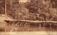Pont sur la Leraba. Affluent du fleuve Comoé,  cette rivière délimite par endroit la frontière entre la Haute-Volta et la Côte d’Ivoire. Elle doit être franchie pour aller d’Ouangolodougou à Niangoloko, sur la route qui permet de gagner la Haute-Volta depuis la Côte d’Ivoire. Ce pont sommaire était donc un passage obligé pour les voyageurs se rendant ou venant au port d’Abidjan, la fenêtre maritime de la colonie voltaïque. Faute de voies navigables suffisantes (les cours d’eau n’étaient utilisés que sur des tronçons et de manières saisonnières) et en attendant l’arrivée tardive du chemin de fer (la ligne d’Abidjan ne devait atteindre Bobo-Dioulasso qu’en 1932 et Ouagadougou en 1954), les infrastructures routières ont été développées assez tôt en Haute-Volta. - « Privée de débouchés naturels et de voies ferrées, la Haute-Volta est, par contre, sillonnée d’admirables routes. Beaucoup d’autos la parcourent. Elles assurent la vie du pays. Le gouvernement en a, pour son compte, une soixantaine, postales et autres ; c’est un véritable parc d’armée. Les autos, et non le chemin de fer, ici comme ailleurs, sont l’avenir » (1). Sources : (1) Morand, Paul, A.O.F. de Paris à Tombouctou, Paris, Flammarion, 1928.