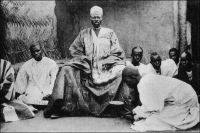 Naba (chef) de Canton entouré de ses pages. – « Avant le déjeuner, à Ouaygouya, où nous fîrmes étape, je suis allé voir le Naba ; c’est le roi du pays Mossinord ; ce Naba est en rivalité avec son confrère du sud, le Moro-Naba, roi de Ouagadougou. Sans nous, ces tyranneaux auraient vidé depuis longtemps leur querelle par les armes. Celui-ci ne parle pas français ; il est magnifique ; vrai Sarrasin de légende, haut de deux mètres, drapé dans une belle robe de soie blanche, tout enturbanné de blanc, portant avec une agressive dignité un ventre énorme, une dizaine de gros sachets magiques rouges pendus autour du cou. On le dit riche et il reçoit très poliment mes dons, avec un parfait mépris. [...] Ce Naba me fait penser aux anciens rois nègres, aux roitelets du Sénégal du XVIIè ou du XVIIIè siècle. N’est-il pas pareil à ce « petit Brac » que décrit ainsi Labat : « Tout l’habit et le baudrier étaient parsemés de gris-gris enveloppés fort proprement dans du drap écarlate, du maroquin rouge ou des peaux de bêtes sauvages. » (1). Paul Morand, qui raconte sa rencontre avec les autorités traditionnelles de Haute-Volta à l’occasion d’un périple à travers l’AOF à la fin des années 1920, se méprend sur le rôle stabilisateur de la France au Mossi. Contrairement à ce qu’il croit, les royaumes du Mossi ont une organisation politique pérenne. C’est à elle qu’on attribue le fait qu’ils aient résisté à toutes les incursions, y compris à la conquête islamique, depuis leur formation au XIIè siècle et jusqu’au début des avancées occidentales au XVIIIè siècle. Ils ont ainsi échappé à la traite négrière, et constituent de ce fait, un formidable réservoir de main d’œuvre auquel le colonisateur fera systématiquement appel. Par ailleurs, Paul Morand convoque un peu hâtivement Jean-Baptiste Labat, l’auteur de Nouvelle relation de l’Afrique occidentale, pour sa description des roitelets du Sénégal. On sait – et cela avait déjà été publié lorsque Morand a écrit ces lignes – que l’ecclésiastique n’a jamais mit les pieds en Afrique, et s’inspirait dans cet ouvrage des mémoires d’un administrateur colonial. Source : (1) Morand, Paul, A.O.F. de Paris à Tombouctou, Paris, Flammarion, 1928.