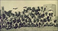 Ouagadougou, groupe de petits élèves de la classe de français. – « La première caravane de Sœurs Blanche arrivait au Mossi, le 3 décembre 1912. [...] Ainsi fut fondée, en 1921, l’école cléricale. [...] Presque tous ses élèves sont des enfants de chrétiens de Ouagadougou (quelques exceptions sont faites pour des enfants de païens). Cependant les succursales et les postes avoisinants envoient aussi leurs garçonnets. [...] Ces enfants nous arrivent vers 6, 7 et 8 ans ; en principe, ils font 5 années de primaire ; en pratique c’est six ans pour beaucoup. Notre école est donc partagée en cinq cours. Une Sœur est chargée de la direction de l’école ; une autre de la première classe. [...] Débutant jeunes à l’école, doués d’une bonne mémoire, nos enfants apprennent vite à lire et leur prononciation est bonne, sauf pour certains sons : S et Ch, E et è, J et Z que les indigènes confondent facilement. [...] Quand ils nous arrivent, ce sont de petits sauvageons au regard apeuré, au geste craintif. Ils connaissent les Pères mais non la Sœur. Pendant quelques jours, ils salueront d’un gentil « Bonjour, mon père ». L’un deux imagina cette définition : « Une Soeur, c’est un père sans barbe ». » Source : Thevenoud, Mgr Joanny, Dans la boucle du Niger, Namur, éditions Grands Lacs, 1938.