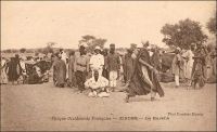 Zinder, le marché. – Le général Gouraud, figure de la conquête coloniale, décrit ainsi Zinder et son marché en avril 1902 - il était alors commandant -, tandis qu’il y rentre pour la première fois : « Zinder est le grand centre de transit de cette partie de l’Afrique centrale. […] Au Nord, à 1500 mètres [de Zinder], se trouve la ville Targuie de Zengou. […] On y rencontre des Tripolitains, quelques Touareg. Elle compte 4 à 5000 habitants. […] Le marché de Zengou est animé. On y trouve en particulier de beaux cuirs, les bottes en filali de toute l’Afrique centrale et que nous portons nous-mêmes, des brides brodées ; les bijoux ne valent pas les délicats filigranes des bijoux soudanais et sénégalais ; il y a de jolies calebasses ouvragées de toutes dimensions, la calebasse pouvant servir d’écuelle aussi bien que de malle aux femmes du pays, qui y empilent leurs étoffes et leurs ustensiles et la portent sur la tête. On y voit des musiciens, des danseuses, aux cadences lentes et balancées, un homme-orchestre. Il y a encore sur le marché de Zengou du sel de Bilma, comme à Tombouctou du sel de Taodénit » (1) – La carte, signée « Photo Combier Mâcon », fait assurément partie de la production de la maison CIM (Combier imprimeurs à Mâcon). Cette entreprise, fondée par Jean Combier avant la première guerre mondiale, éditera quelques 2 millions de carte postales essentiellement consacrées aux régions françaises – colonies comprises – entre 1907 et 1982 (2). Source : (1) Gouraud, Général, Zinder, Tchad - Souvenirs d'un Africain, Paris, Plon, 1944. (2) Combier, Marc, Un siècle de cartes postales, Paris, Alternatives, 2005.