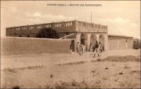 Zinder, quartier des commerçants. - « Zinder est le grand centre de transit de cette partie de l’Afrique centrale. […] Au Nord, à 1500 mètres [de Zinder], se trouve la ville Targuie de Zengou. […] On y rencontre des Tripolitains, quelques Touareg. Elle compte 4 à 5000 habitants. […] Le marché de Zengou est animé. On y trouve en particulier de beaux cuirs, les bottes en filali de toute l’Afrique centrale et que nous portons nous-mêmes, des brides brodées ; les bijoux ne valent pas les délicats filigranes des bijoux soudanais et sénégalais ; il y a de jolies calebasses ouvragées de toutes dimensions, la calebasse pouvant servir d’écuelle aussi bien que de malle aux femmes du pays, qui y empilent leurs étoffes et leurs ustensiles et la portent sur la tête. On y voit des musiciens, des danseuses, aux cadences lentes et balancées, un homme-orchestre. Il y a encore sur le marché de Zengou du sel de Bilma, comme à Tombouctou du sel de Taodénit ». Source : Gouraud, Général, Zinder, Tchad - Souvenirs d'un Africain, Paris, Plon, 1944.