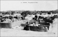 Zinder, vue générale du Berny – Description de Zinder en avril 1902, quand y entre le commandant Gouraud : «La ville est entourée d'un fort rempart à dents de scie en bon état, rappelant celui de Sikasso […] les rues de la ville sont étroites, comme dans toutes les villes soudanaises. Peu de maisons en terre, beaucoup de cases en paille, d'immenses trous, là où on a pris la terre, des amas de blocs de grès arrondi et lavé par les pluies, une des caractéristiques du pays. La ville est sale, les vautours et les chiens étant seuls chargés de la voirie. Beaucoup de beaux arbres dans la ville et aux environs. […] Zinder est le grand centre de transit de cette partie de l’Afrique centrale. […] Au Nord, à 1500 mètres [de Zinder], se trouve la ville Targuie de Zengou. […] On y rencontre des Tripolitains, quelques Touareg. Elle compte 4 à 5000 habitants. […] Le marché de Zengou est animé. On y trouve en particulier de beaux cuirs, les bottes en filali de toute l’Afrique centrale et que nous portons nous-mêmes, des brides brodées ; les bijoux ne valent pas les délicats filigranes des bijoux soudanais et sénégalais ; il y a de jolies calebasses ouvragées de toutes dimensions, la calebasse pouvant servir d’écuelle aussi bien que de malle aux femmes du pays, qui y empilent leurs étoffes et leurs ustensiles et la portent sur la tête. On y voit des musiciens, des danseuses, aux cadences lentes et balancées, un homme-orchestre. Il y a encore sur le marché de Zengou du sel de Bilma, comme à Tombouctou du sel de Taodénit ». Source : Gouraud, Général, Zinder, Tchad - Souvenirs d'un Africain, Paris, Plon, 1944.