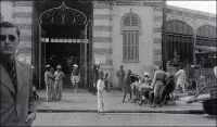 Dakar, devant le marché européen, janvier 1941. Photo d’amateur, légende manuscrite. – Il s’agit, bien sûr, du marché Kermel. L’époque – début 1941 - est un peu particulière, puisque Dakar est alors la capitale vichyste de l’Afrique noire. Elle vient de repousser, quelques mois auparavant, une tentative de débarquement des forces de la France libre – dirigées par De Gaulle lui-même - et de la marine britannique, les 23 et 24 septembre 1940. La farouche opposition dakaroise tient pour partie à la défiance de la marine française envers les Anglais, qui venaient de mener une attaque très destructrice et meurtrière contre la flotte nationale dans le port algérien de Mers-el-Kébir. Elle tient aussi à la personnalité du gouverneur-général Pierre Boisson, nommé deux mois plus tôt à la tête de l’AOF et de l’AEF par Vichy (alors même que l’AEF, qu’il gouvernait jusque là, avait formellement rallié le gaullisme au lendemain de son départ de Brazzaville pour Dakar). Il resta encore fidèle à Pétain  jusqu’au 22 novembre 1942, deux semaines après le débarquement des troupes américaines au Maroc et alors que la plupart des colonies vichystes avaient rejoint le camp des alliés. Signe de sa détermination antigaulliste, il négocie son ralliement à Darlan – le chef de l’armée française d’Afrique qui vient de passer dans le camp des alliés – en excluant toute ingérence gaulliste sur le territoire. Durant les tractations, le 19 novembre 1942, le résistant Adolphe Gaétan fut même fusillé à Dakar, pour « menées gaullistes ». Pierre Boisson sera remplacé en novembre 1943, poursuivi et révoqué par le tribunal d’Alger durant la guerre puis condamné par la Haute cour de justice en 1948, peu avant sa mort. La bataille de Dakar, en septembre 1940, fit de gros dégâts et de nombreuses victimes civiles dans la ville. Elle se solda par un fiasco militaire pour les assaillants, et par un cuisant revers politique pour De Gaulle et Churchill, qui faillit alors être démissionné.