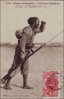 Tirailleur sénégalais. - 212 000 Africains de toute l’AOF, prirent part en tant que tirailleurs sénégalais aux hostilités de la Grande guerre, dont 165 000 sur le sol métropolitain. 30 000 furent tués. Le corps des tirailleurs sénégalais avait été créé en 1857 par Louis Faidherbe, alors gouverneur général de l’AOF, pour palier, en cette époque de conquête coloniale, le déficit de troupes venant de Métropole. Initialement composés d’esclaves rachetés à leurs maîtres africains et affranchis et de volontaires issus des élites locales, les régiments de tirailleurs sénégalais s’apparentent à des troupes mercenaires. Mais la mobilisation de tous les Africains de plus de 18 ans décidée en 1915, et leur engagement pour défendre la Nation, vont en faire un corps d’engagés et de conscrits des plus légitimes. 17 régiments de tirailleurs sénégalais participent à la bataille de la Somme, subissant d’importantes pertes qui vaudront au Général Mangin, par ailleurs promoteur des troupes africaines, le surnom de « boucher des noirs ». - Cette remarquable photo, publiée en carte postale,  fait partie du travail du célèbre photographe et éditeur dakarois Edmond Fortier (1862-1928). On lui doit une somme importante de clichés sur l’Afrique de l’Ouest en général et sur le Sénégal en particulier ; il a publié en tout 3300 clichés originaux. M. Fortier tenait boutique et vivait avec ses deux filles blondes et son boy Seydou Traoré, à l’angle de la rue Dagorne et du boulevard Pinet-Laprade, tout près du marché Kermel.