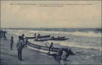 Saint-Louis, la plage à Guet N’Dar, premiers départs pour la pêche, le lancement des pirogues. – Les habitants de Guet N’Dar, le quartier de Saint-Louis situé entre le petit bras du fleuve Sénégal et l’océan, sont réputés pour leurs qualités de pêcheurs et de navigateurs. A l’époque coloniale, la pêche, activité artisanale et spécifiquement indigène, était peu considérée par les acteurs économiques établis. Ainsi, elle n’était pas prise en compte par les Chambres de commerce, d’agriculture et d’industrie de Dakar et de Saint-Louis, qui géraient pourtant les activités maritimes de la colonie - notamment en exploitant les ports fluvio-maritimes grâce à une flottille de remorqueurs et chalands. Depuis cette époque, la pêche piroguière sénégalaise a connu une forte expansion. Au cours des cinquante dernières années, le nombre d’embarcations traditionnelles a été multiplié par cinq, et les prises de poisson continuent encore actuellement de croître, atteignant 361 000 tonnes en 2007. Directement ou indirectement, le secteur emploie 15 % de la population active du Sénégal. Les pêcheurs de Saint-Louis louent quelques fois leurs services à en capturant du poisson pour des flottes étrangères stationnées au large. Contrairement à une idée souvent véhiculée par la presse occidentale et sénégalaise, les pêcheurs sénégalais ne sont que très marginalement impliqués dans l’émigration irrégulière et périlleuse vers les îles Canaries, avant poste des frontières européennes (1) – Le photographe Pierre Tacher (1875-1938), qui signe ce cliché, fut l’éditeur de cartes postales le plus prolixe de Saint-Louis au début du Xxème siècle. Il repose au cimetière de Sor, un quartier de Saint-Louis, aux côtés de son fils que l’on peut voir sur une autre image du site. Sources (1) Sall, Aliou et Morand, Pierre. 