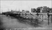 Le wharf de Rufisque pendant la traite des arachides. – La ville de Rufisque, qui s’est développée progressivement à partir du XIVème  siècle sur un site initialement occupé par des villages de pécheurs, devient au cours du XIXème siècle le principal centre de traitement et d’exportation de l’arachide. Elle s’est imposée dans cette activité, grâce à son port et à sa situation géographique, à la porte du Cayor. En 1880, 23 000 tonnes d’arachides sont exportées depuis Rufisque, soit plus de la moitié des exportations de la colonie, et en 1909, 45 000 tonnes. Centre commercial et administratif important, Rufisque devient une commune avant même Dakar, le 12 juin 1880. Mais elle connaît dès la fin des années 1920 un déclin inexorable. Ses activités portuaires sont concurrencées par celles d’autres villes, Dakar et Kaolack notamment. Son rayonnement a pali depuis que Dakar est devenue en 1902 la capitale de l’AOF et reçoit la majeure partie des investissements publics. L’âge d’or de Rufisque s’achève définitivement avec la crise économique des années 1930. A visiter : http://www.rufisquenews.com/rufisque_une_ville_une_histoire.html