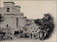 Cathédrale de Saint-Louis, sortie de la messe. – La ville de Saint-Louis s’est développée autour du fort central, en un quartier « Kertian » au sud, où sont vivent les chrétiens, et un quartier « Lobo » au nord, abritant les esclaves et les employés, et où domine l’islam.  La ville comptait, en 1758 « 1401 habitants dont 169 chrétiens et 647 esclaves ». Au XVIIIème siècle, la vie religieuse des chrétiens est animée par les aumôniers des navires de commerce, qui viennent à la charge de la Compagnie des Indes, et restent parfois à poste fixe pendant quelques mois. Durant l’occupation anglaise (1758-1779), aucun prêtre n’est autorisé à rester à Saint-Louis, et à l’exception de l’éphémère passage deux missionnaires,  rescapés du naufrage du navire négrier qui les emmenait à Cayenne via Gorée et recueillis par le gouverneur anglais en 1778, toute l’activité religieuse chrétienne est organisée par les fidèles eux-mêmes. Avec la reprise de Saint-Louis par les Français en 1779, l’Eglise se réinstalle, en la personne de l’Abbé Déglicourt, un des missionnaires rescapés, qui avait été expulsé sur un bateau anglais, lequel fut capturé par des corsaires français à seulement sept lieues de Douvres ! En sommeil après la Révolution, l’activité de l’Eglise est relancée en 1819 avec l’implantation de la communauté des Sœurs de Saint-Joseph de Cluny (suivie en 1841 par celle des Frères de Ploërmel), mais surtout par la construction dans le quartier Kertian de la cathédrale entre 1827 et 1828. C’est la première église bâtie dans la ville, qui n’avait disposé jusqu’alors que de lieux de culte sommaires, chapelle du fort, maison de l’aumônier, simple chambre dans les bâtiments administratifs puis chapelle à l’hôpital.