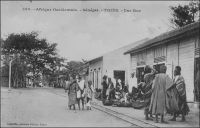 Thiès, une rue. - Thiès est le chef lieu du cercle du même nom, lequel compte, en 1948, une population de 2797 Européens et 272 692 Africains, dont 144 330 Ouoloffs, 91 754 Sérères et 12 369 Peuhls, pour une densité de 40,5 hab/km². La ville elle-même compte 24 783 Africains, 1350 Européens et 624 étrangers. Par comparaison, le recensement mené pour la ville de Dakar au début de cette même année 1948, dénombre 192 567 habitants, dont 167 055 non européens (troupes comprises), 16 112 Français, 500 étrangers (non compris les Libano-Syriens), 400 Français métis, 4500 Libano-Syriens et 4000 ressortissants étrangers non européens (principalement Portugais). Source : Guid’AOF, édition 1948. - Cette photo fait partie du travail du célèbre photographe et éditeur dakarois Edmond Fortier (1862-1928) à qui l’on doit une somme importante de clichés sur l’Afrique de l’Ouest en général et sur le Sénégal en particulier ; il a publié en tout 3300 clichés originaux. M. Fortier tenait boutique et vivait avec ses deux filles blondes et son boy Seydou Traoré, à l’angle de la rue Dagorne et du boulevard Pinet-Laprade.
