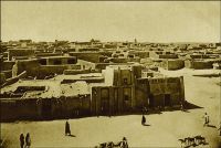 Tombouctou, vue générale. (années 1920) – « J’ai été à Tombouctou, en dessous du royaume de Barbarie, en pays très arides dans les terres » (1). « Tombouctou, disent les vieux chroniqueurs soudanais, est le lieu de rencontre de ceux qui voyagent en pirogue et de ceux qui cheminent à chameau. […] Quelques casernes ocres à créneaux, des drapeaux français et des maisons carrées, de teinte mastic, sans une ombre, sans un relief. […] Tombouctou, qui fut jadis une cité de plus de cent mille âmes, n’est plus qu’un village de cinq mille habitants. […] Cependant l’impression que laisse Tombouctou est très foret. C’est la fin du monde nègre, de la beauté des corps, des gras pâturages, de la joie de vivre, du bruit, des rires… » (2). Sources : (1) Benedetto Dei, premier européen à venir à Tombouctou en 1469. (2) Morand, Paul, A.O.F. de Paris à Tombouctou, Paris, Flammarion, 1928.