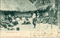Palaver-Sitzung(Togo). Séance de palabre au Togo. - Ce tableau édifiant célèbre les sages traditions togolaises en matière de négociation. Il semble opportunément scénarisé pour illustrer certaines des options de la politique coloniale allemande. D’une part, il ne peut s’agir d’une scène de vie saisie à l’improviste par le photographe. Le matériel et les temps de pose requis pour capturer une telle image, en ce tout début du XXème siècle, nécessitaient en effet une certaine organisation. Il a sûrement fallu la préparer, la jouer, la rejouer  et attendre suffisamment longtemps –dans une grande immobilité !- pour impressionner la plaque de verre… D’autre part, cette photo porte les indices du message qu’elle est censée véhiculer, en l’occurrence justifier la délégation de l’exercice du droit aux chefs coutumiers. Ainsi, l’image présente clairement l’assemblée telle un tribunal. Elle est présidée par des édiles locaux siégeant en costume presque officiel. L’œil de la population est représenté par l’abondante assistance répartie de part et d’autre de la cour –et de la cours. Enfin le sérieux de la chose et l’adoubement de la colonie sont attestés en la personne d’un officiel allemand en uniforme, consignant les décisions par écrit. Les Allemands avaient en effet pris le parti de confier aux autorités indigènes les tâches de justice. Cette délégation présente plusieurs avantages. Elle fait porter sur les élites locales l’éventuel mécontentement lié à l’application de lois allemandes particulièrement sévères pour les indigènes. Elle permet aussi d’économiser substantiellement sur le personnel colonial dédié. L’économie des dépenses est un principe central dans la gestion du Togo. Ce territoire est considéré comme la colonie modèle par Berlin, car très tôt il rapporte à l’Allemagne plus qu’il ne coûte.