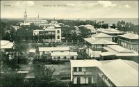 Lomé, Stadtteil der Europäer. - Cette photo du « quartier des Européens » de Lomé à l’époque allemande ne représente pas, paradoxalement, le quartier appelé  Yovokomé, « le village des blancs » en mina, l’une des langues vernaculaires. En réalité, elle montre la zone commerçante de la ville - avec la cathédrale achevée en 1902 au fond - où exerçaient et logeaient marchands européens et africains. Le quartier administratif, abritant les services de la colonie et les logements des fonctionnaires allemands, justement désigné comme Yovokomé par les Loméens, se trouve dans le dos du photographe. La structure de la ville, avec ce quartier administratif un peu à l’écart du centre historique, tient à sa vocation commerciale initiale. Là, et contrairement aux autres capitales du continent où l’administration a accaparé tous les sols urbains, la propriété privée et individuelle des terrains est reconnue dès les origines. Les autorités font d’ailleurs dresser un cadastre dès leur arrivée en 1896, bien après l’installation des commerçants il est vrai. Ceux-ci, venus faire fortune, achètent et revendent les lots immobiliers comme toute autre marchandise, au point qu’il y a eu plus de mutations foncières dans la ville au cours de la brève période allemande (1884-1914) que depuis ! Les autorités coloniales se sont installées en bordure ouest du centre si convoité, créant une zone administrative géographiquement distincte du pôle des affaires. Cette séparation en fonction des activités, matérialisée au sol par le tracé ferroviaire, existe toujours aujourd’hui.