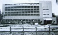 Lomé, l’hôtel Le Bénin en cours d’achèvement. –Premier établissement aux normes modernes d’Afrique de l’Ouest, il est bâti en un temps record, pour être achevé le 27 avril 1960, date de la proclamation d’indépendance. Il devait en effet héberger les personnalités étrangères invitées à la cérémonie. Sylvanus Olympio, le premier président, souvent considéré comme l’artisan de cette nouvelle souveraineté, ne devait pas achever son mandat. Il est assassiné le 13 janvier 1963, vraisemblablement à l’instigation de la France. Paris et son « monsieur Afrique » d’alors, Jacques Foccart, n’auraient pas supporté la volonté d’émancipation du chef d’Etat togolais. Celui-ci venait d’annoncer sa sortie prochaine de la zone CFA, au profit d’une monnaie qu’il souhaitait voir adossée au mark allemand. Réveillé dans la nuit par l’intrusion de militaires à son domicile, il s’était réfugié dans le parking de l’ambassade américaine voisine. Mais il est livré à ses bourreaux par l’ambassadeur lui-même, qui l’avait pourtant assuré de sa protection en le découvrant caché dans une voiture. Selon les témoignages, les aveux et les époques, son exécution a été attribuée à trois hommes distincts : le sergent chef Etienne Gnassingbé, qui finira par prendre le pouvoir en 1967 sous le nom de Gnassingbé Eyadéma, un autre sous-officier togolais nommé Robert Adéwi, de sinistre  mémoire, et le commandant français Georges Maitrier. Le fils de Sylvanus Olympio devait longtemps porter le flambeau de l’opposition, avant de se rallier récemment au pouvoir, occupé depuis la mort du général Eyadéma par un de ses fils. La fête nationale du Togo, fixée au 13 janvier du temps du président Eyadéma, commémore ainsi à la fois la date d’un assassinat et celle du premier coup d’Etat sanglant de l’Afrique indépendante. – Cette photo provient du fonds de Léon Anselmo, qui vécut au Togo et prit part à la construction de nombreux édifices dont l’hôtel Le Bénin.