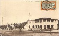 Le Bureau des Douanes à Lomé. – Ce bâtiment, construit en 1903 par les Allemands juste en face du wharf, a été démoli en 1983, laissant place à un centre commercial moderne comptant des salles de cinéma, un casino, une boite de nuit et un hôtel. Les douanes jouaient un rôle capital dans le dispositif colonial allemand. Elles fournissaient en effet la majeure partie des ressources budgétaires du Togo, qui finit par ne plus rien coûter à la métropole à partir de 1906. Les Allemands considéraient de ce fait le Togo comme « Musterkolonie », la colonie modèle. Les marchandises pour tout le territoire, qui devaient être obligatoirement débarquées par le wharf -et donc directement devant la douane-, étaient soumises à une taxe de 10%. Seuls certains articles, comme les sacs, les bouteilles ou les wagons, bénéficiaient d’une franchise douanière. Les Anglais et les Français qui succèdent aux Allemands après la défaite locale de 1914, maintiennent dans un premier temps un système douanier comparable à celui de leurs prédécesseurs. Ensuite, tandis que les Anglais adoptent le même régime douanier au Togo britannique qu’en Gold Coast, les Français instaurent au Togo sous mandat un statut moins favorable qu’au Dahomey et créent ce faisant une concurrence entre les deux territoires mitoyens qui obligea à rétablir un poste de douane à Aného et un contrôle de la frontière sur le Mono. Progressivement, la situation est normalisée, et peu avant la seconde guerre mondiale le régime douanier des deux territoires est aligné sur celui du reste de l’AOF.