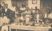 Ecole professionnelle de la mission catholique de Lomé, cordonnerie. Carte postale éditée par les missions africaines de Lyon. - Cordonniers, menuisiers, forgerons, serruriers, imprimeurs et même relieurs, le Togo dispose dès l’époque coloniale allemande d’ouvriers et d’artisans bien formés grâce à l’école professionnelle de Lomé. L’établissement, géré par les pères de la mission catholique, est situé à l’angle de l’avenue de la Libération) et de l’actuelle rue Aniko Palako. Les élèves, qui sont admis après quatre ans d’école primaire, reçoivent en quatre années une formation dont la qualité est reconnue dans tout le territoire, et même au-delà des frontières dans toutes la région.