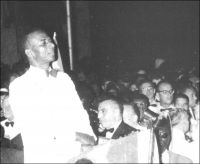 Au soir du 26 avril 1960, Sylvanus Olympio et les Togolais attendent les 101 coups de canon qui marqueront, à minuit, l’indépendance formelle du Togo. – Proclamée dès les premiers instants du 27 avril,  l’indépendance était plus une cérémonie solennelle qu’un bouleversement institutionnel. Elle intervenait en effet deux ans jour pour jour après l’arrivée de S. Olympio à la tête du premier gouvernement du Togo indépendant, le 27 avril 1958. Des accords signés entre la République autonome du Togo (proclamée le 30 août 1956) et la France, venaient alors de donner quasiment tous les pouvoirs – hormis les relations extérieures, la monnaie, les changes et la Défense, conservés par la tutelle française - au chef de la majorité à l’assemblé territoriale togolaise. Ces dispositions avaient été négociées par Nicolas Grunitzky, adversaire politique et propre beau-frère d’Olympio, aux affaires depuis 1951, auprès de l’ONU et de Paris - ancienne colonie allemande, le Togo était sous la tutelle des Nations Unies, confié par celles-ci à la gestion de la France.  Ce statut que n’auraient pas renié les plus nationalistes devait finalement faire de  Sylvanus Olympio l’homme des indépendances – technique d’abord, formelle ensuite -, le parti de Grunintzky, homme lige de Paris aillant perdu les élections législatives de 1958. Les festivités du 27 avril 1960, furent, de l’avis de tous mémorables et parfaitement orchestrées. La radiodiffusion d’Outre-Mer rendit compte de l’événement, l’INA en propose un intéressant extrait en archive : http://www.ina.fr/histoire-et-conflits/decolonisation/audio/PHD86080309/ceremonie-d-independance-du-togo-a-la-chambre-des-deputes-togolaise.fr.html