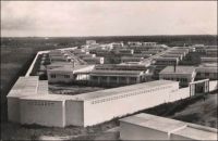 Lomé, vue générale de l'hôpital de Tokoin - Le CHU de Lomé, bâti par tranches entre 1951 et 1954 sur l’emplacement de l’ancien aérodrome de 1931, remplace l’hôpital Reine-Charlotte de Lomé, principale institution hospitalière du Togo depuis son ouverture en 1909. Son implantation sur le plateau de Tokoin initie l’extension de la ville au-delà de la lagune. On voit sur cette photo, qui doit immédiatement suivre les travaux – il n’y a encore aucun arbre dans l’enceinte de l’hôpital –, que le quartier est totalement vide. Tokoin va dès lors rapidement se peupler et s’étendre, comptant 7000 habitants en 1959, et rassemblant de nos jours plus des deux tiers de la population de Lomé. L'architecte de ce nouvel établissement hospitalier, Henri Crouzat, est également à l'origine du plan d'urbanisme de Lomé datant de 1948. Il reste cependant plus connu pour son oeuvre littéraire. « Azizah de Niamkoko », publié en 1959 et porté à l’écran en 1986 par Patrick Jamain sous le titre de « Azizah, fille du fleuve », est un célèbre roman à clef décrivant le Togo colonial. Il aurait valu à son auteur d’être réexpédié manu militari en métropole. « L'île du bout du monde », son premier roman avait été édité en 1958 et porté à l'écran la même année par le réalisateur français Edmond T. Gréville ; Crouzat assurant à la fois l’adaptation et les dialogues.