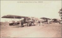 Sokodé, l’arrivée des aéroplanes français au Togo. – L’histoire de l’aviation togolaise est assez ancienne, puisque les autorités coloniales ont fait établir, dès l’entre guerres, une série de terrains de secours, dont 2 (Lomé et Mango) ouverts à l’année et 23 secondaires uniquement praticables en saison sèche. Ces installations sommaires étaient destinées à répondre aux besoins croissants des raids touristiques. A la même époque, en 1934 ou 1936 selon les sources, l’aéroclub de Lomé voit le jour, sous l’impulsion de l’avocat Viale qui l’animera jusqu’en 1939. Les pilotes amateurs volent alors sur un monoplan Potez de type 60 P2 et sur un biplan Caudron C59. L’aéroclub du Golfe, qui est le plus ancien d’Afrique de l’Ouest, fonctionne encore 75 ans plus tard. Le Togo fut également le pionnier dans la région pour la construction aéronotique amateur, avec un monoplace monoplan à aile basse mu par un moteur Volkswagen, conçu et fabrique dans les années 1970 par le mécanicien Jean Camérini. – Carte postale éditée par A. Accolatsé. Alex Accolatse avait commencé sa carrière de photographe à la toute fin du XIXème siècle en Gold Coast, avant de venir s’installer en 1900 à Lomé où il exerça jusqu’en 1956 et s’éteignit en 1975 à 95 ans.