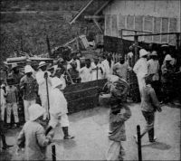 Arrivée du gouverneur du Togo prisonnier à Porto Novo, en 1914. – Il s’agit du commandant Von Doering, qui assurait l’intérim du duc de Mecklemburg en congé lorsque la Grande Guerre éclata. Les parties en présence n’imaginaient pas que le conflit puisse se porter dans la région. Von Doering, avait d’ailleurs vainement proposé à deux reprises par télégramme des 4 et 5 août 1914,  aux gouverneurs du Dahomey, de Gold Coast et d’AOF, de neutraliser son territoire « pour ne pas donner aux Africains le spectacle de guerres entre Européens ». Von Doering, qui ne disposait que d’une force de police insuffisante pour résister à la coalition des troupes britanniques de Gold Coast et françaises du Dahomey (lesquelles se trouvaient alors ponctuellement renforcées par un bataillon venu de Dakar pour soumettre la turbulente peuplade des Holi), organisa la défense du seul site stratégique pour l’Allemagne, la station de radio transmission de Kamina proche d’Atakpamé. Défait après une vaillante résistance, il tente de négocier la reddition 25 août, non sans avoir détruit les installations de Kamina la nuit précédente. Sa reddition, sans qu’aucune condition n’ait été consentie par les vainqueurs, est effective le 26 août. Les prisonniers allemands sont internés au Dahomey, et la presse germanique mène en février 1915 une campagne pour dénoncer leurs conditions de détention. En fait, il se serait s’agit d’une action de propagande, destinée à justifier les mesures prises à l’égard des prisonniers français du camp de représailles d’Ahlen Falkehberger, en Allemagne.