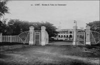 Lomé, entrée du palais du gouverneur – Construit de 18989 à 1905, il abritait les bureaux au rez-de-chaussée et les appartements du gouverneur à l’étage, selon le modèle habituel des bâtiments coloniaux. Le gouverneur August Kohler (1858 – 1902), qui était au Togo depuis 1895, décida en 1898 l’emplacement à 250 m de la plage. Pour que l’ensemble de l’édifice puisse être vu depuis les navires en mer, et ce malgré un talus qui bordait le rivage, le bâtiment reçu un sous bassement de 3,50 m. Sur ce cliché, on distingue, au mat de drapeau du bâtiment, les couleurs françaises. L’édifice devait continuer en effet à abriter l’exécutif du Togo, durant l’occupation britannique, entre 1914 et 1920, puis sous le mandat français et même après l’indépendance, jusqu’à la construction de la nouvelle présidence, sur un terrain mitoyen, en 1970.