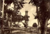 Phare de Cotonou. – « Je suis parti un soir de Lomé et le lendemain matin je suis arrivé à Cotonou, Dahomey : côte basse, toujours, la barre, la plage, la longue rangée d’arbres et le wharf hérissé de grues. Une seule chose distingue Cotonou de Lomé : à Lomé, le phare est à gauche de wharf ; ici, on l’a planté à droite. Mêmes barcasses, mêmes chaloupes à vapeur venant chercher à bord passagers et bagages. Même panier ». Source : Martet, Jean, Les bâtisseurs de royaumes, Paris, Albin Michel, 1934.